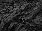 Black white rock background. Dark gray stone texture.  Mountain surface close-up. Distressed, сracked, collapsed, crumbled, broken. 