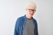 © Krakenimages.com - Young albino blond man wearing denim shirt and glasses over isolated white background winking looking at the camera with sexy expression, cheerful and happy face.