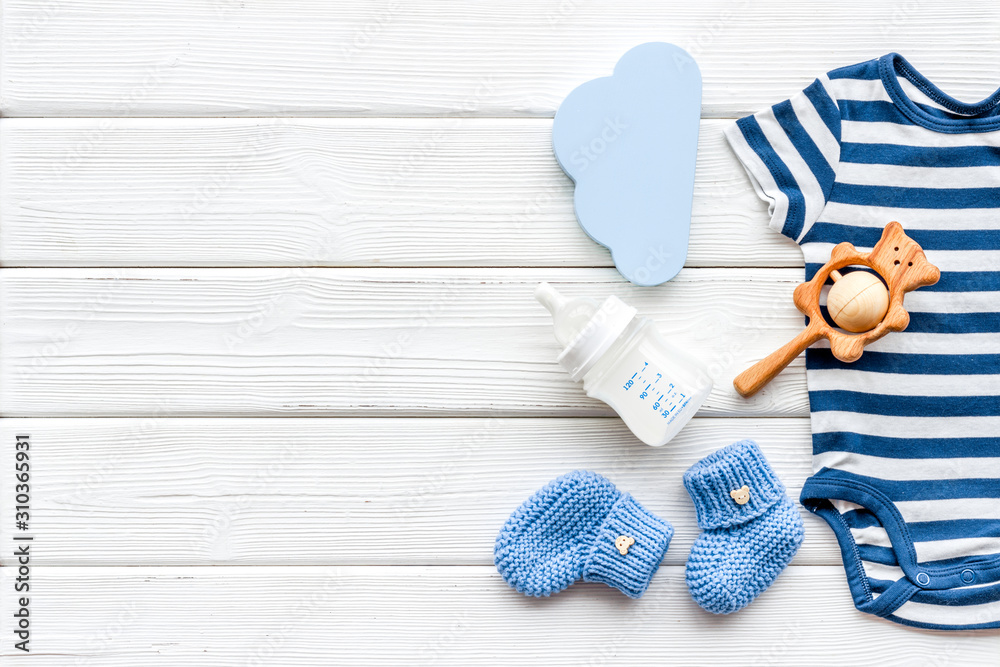 Newborn baby boy set - blue clothes as bodysuit, booties, toys - on white wooden table top-down frame copy space - obrazy, fototapety, plakaty 