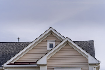 Wall Mural - Reverse double gable close up on luxury single family residential home.  Square single pane gable window. Roof line of traditional home with one gable running one way reverse gables running the other.