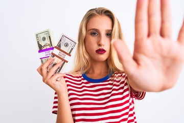 Beautiful woman wearing red striped t-shirt holding dollars over isolated white background with open hand doing stop sign with serious and confident expression, defense gesture