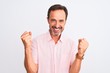 © Krakenimages.com - Middle age handsome man wearing casual pink shirt standing over isolated white background celebrating surprised and amazed for success with arms raised and open eyes. Winner concept.