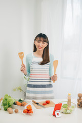 Wall Mural - Beautiful young asian woman reading cooking recipe or watching show while making salad