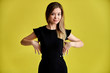 © Вячеслав Чичаев - Portrait of a pretty young smiling girl on a yellow background in a black dress with long straight hair. Standing right in front of the camera, Shows emotions, talks in different poses.