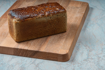 rectangular loaf of wheat bread with a baked shiny crust on the kitchen table.