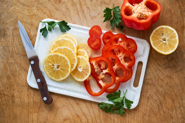 Wall Mural - Slices of lemon and red bell pepper on a white cutting board