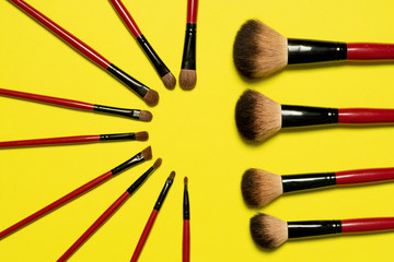 Set of red makeup brushes in circle order on yellow background 