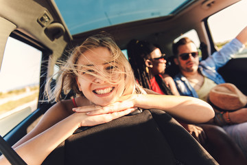 Wall Mural - Three best friends enjoying traveling in the car, sitting in rear seat and having lots of fun on a road trip.