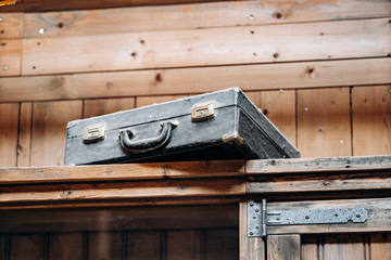 An old battered suitcase on a shelf in the dust. Vintage travel bags are on a shelf. Retro bulky Luggage. Image done in grunge style on rough dirty texture background