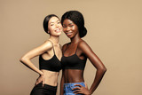 Beauty. Multi Ethnic Group of Womans with diffrent types of skin  together and looking on camera. Diverse ethnicity women -  African and Asian posing and smiling against beige background.