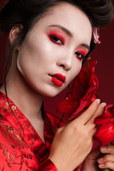 Poster - Image of beautiful geisha woman in japanese kimono holding flowers