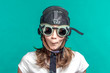 © R - Girl in pilot helmet on a turquoise background.