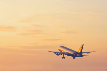 Airplane taking off and rising high in sunset sky