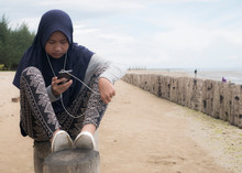 Muslim Girl Listening To Music On Phone On The Beach