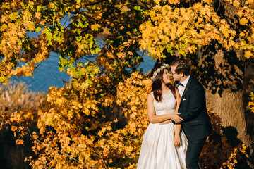 Cute groom with his happy gorgeous brunette bride on the background of a lake