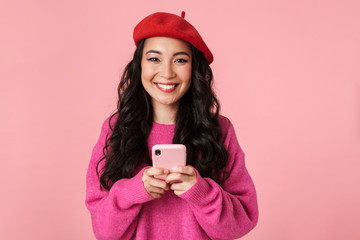 Canvas Print - Image of optimistic beautiful asian girl smiling and holding smartphone