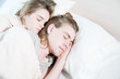 © yanik88 - Close-up of a young couple in bed sleeping in an embrace, hiding behind a blanket. The concept of a young family and healthy sleep