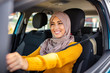 © Dragana Gordic - Portrait of muslim asian young woman driving her car. Arab women driving car. Middle Eastern Woman Driving a Car, Looking Forward. Get driving license concept