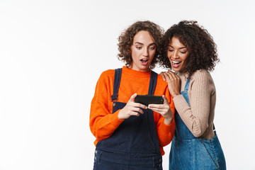 Wall Mural - Multiracial girls friends in denim jumpsuits using mobile phone.