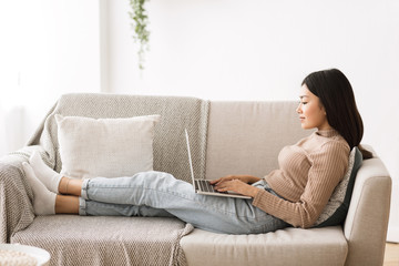 Wall Mural - Lazy weekend. Young girl relaxing on sofa with laptop