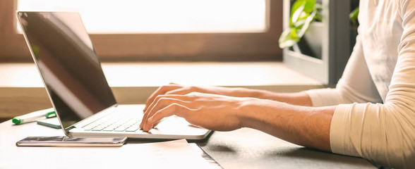 IT developer working on laptop in cafe, typing on keyboard