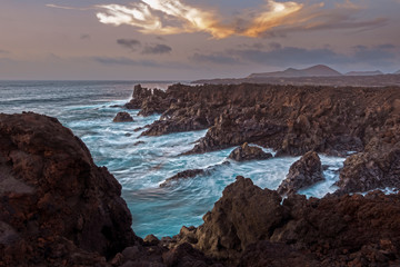 Atardecer en isla volcánica con mar bravo