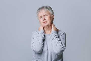 Poster - Senior woman suffering from neck pain on grey background