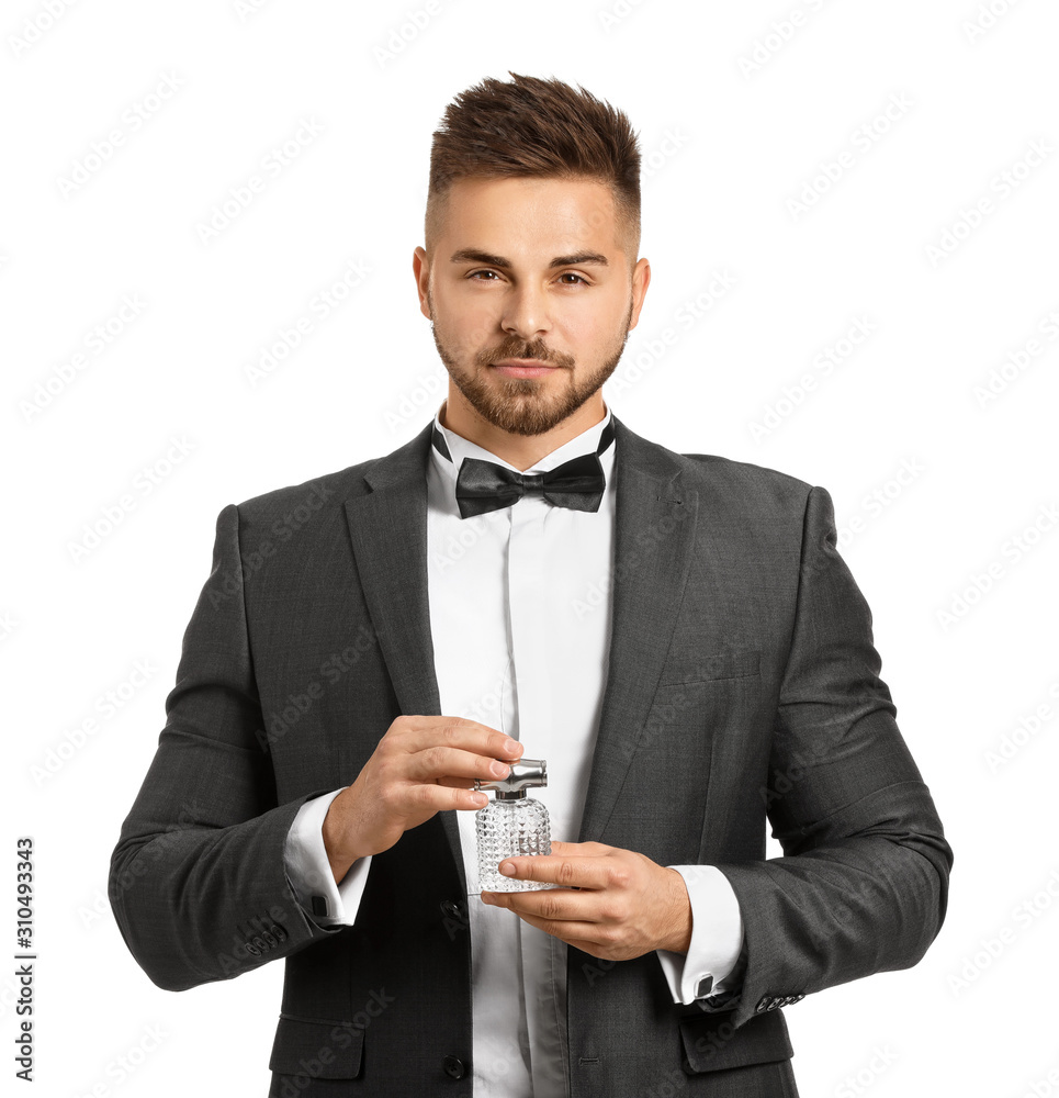 Handsome young man with bottle of perfume on white background