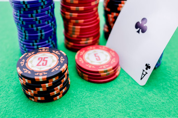 Stack of poker chips with different colors and values ​​next to a card with an ace as a bet