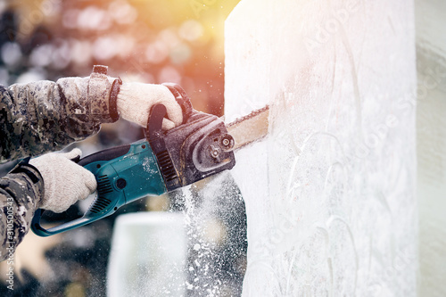 Cuadros en Lienzo Ice sculpture carving man use electric chainsaw cut frozen winter