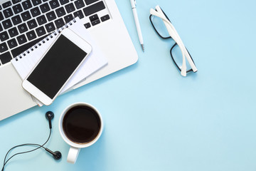 Blue office desk table with notebook, pen, glasses, cup of fresh espresso coffee. Top view with copy space, flat lay