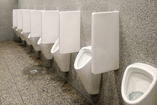 Public Toilet With Gray Walls And Many White Urinals