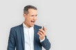 © Viktoriia - Freestyle. Mature businessman standing isolated on white shouting at smartphone angry