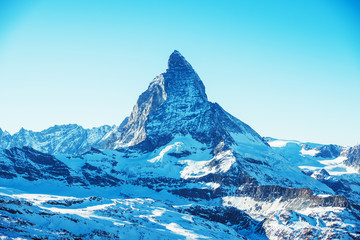 Scenic view on snowy Matterhorn mountain peak in sunny day with blue sky, Zermatt, Switzerland. Beautiful nature background of winter Swiss Alps covered with snow. Famous travel destination.