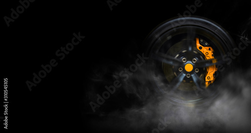 Fotografía Isolated generic sport car wheel with yellow breaks drifting and smoking on a bl