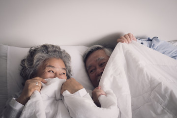 Wall Mural - elderly couple caucasian senior man and woman sleep on bed and smiling in white blanket in bedroom, retirement health care with love lifestyle concept