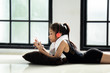 © Rakchanok - Asian little adorable schoolgirl or happy cute girl in dancing suit lie down on the floor, relaxation with colorful headphone and smartphone after practicing or training jazz dance in studio classroom