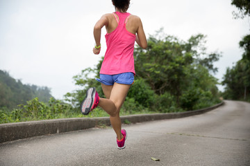 Sporty young woman in sportswear trail running on forest mountain path. Fitness girl jogging in Hong Kong