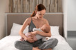 © New Africa - Young woman breast feeding her little baby in bedroom