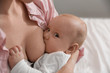 © New Africa - Young woman breast feeding her little baby, closeup