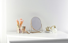 Small Mirror And Makeup Products On White Dressing Table Indoors