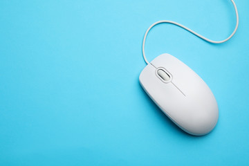 wired computer mouse on light blue background, top view. space for text