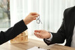 © New Africa - Real estate agent giving key to client at table in office, closeup