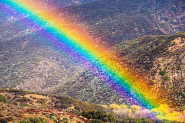 Wall Mural - Bright rainbow on a rainy day in southern California; hills and valleys covered in chaparral visible in the background; Los Angeles County, California