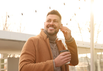 Wall Mural - Man with cup of coffee on city street in morning