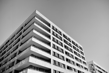 Sun rays light effects on urban buildings. Fragment of modern residential apartment with flat buildings exterior. Detail of new luxury house and home complex. Black and white.