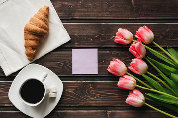 Wall Mural - Cup of coffee with a bouquet of pink Tulip flowers and a croissant for the morning Breakfast