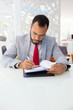 © Mangostar - Serious businessman writing on papers. Focused young African American businessman in eyeglasses sitting at table and working with documents in office. Paperwork concept