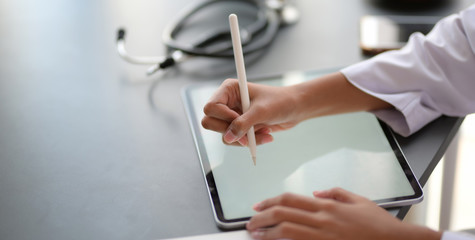 Wall Mural - Cropped shot fo young female doctor working on medical records and exam results with tablet