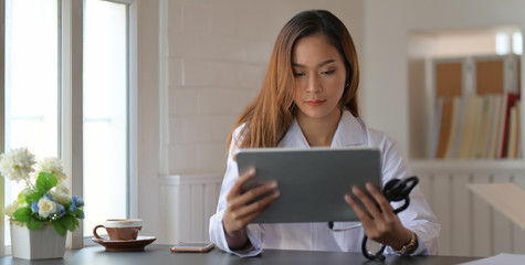 Wall Mural - Young female doctor analysing medical charts with tablet